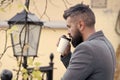 Businessman bearded guy drink coffee outdoors. Hipster hold paper coffee cup and enjoy park environment. Relaxing coffee Royalty Free Stock Photo