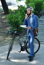 Businessman with bicycle talking on phone and analyzes report