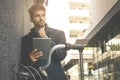 Businessman with bike leaning on wall and holding digita