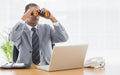 Businessman with binoculars in front of laptop at office