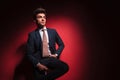 Businessman in black with red tie posing seated in studio Royalty Free Stock Photo