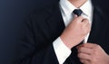 Businessman in black suit and adjusting necktie. Royalty Free Stock Photo