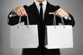 Businessman in a black suit holding a gray paper gift bag. Close up. Isolated background