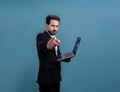 Businessman in black suit holding laptop pointing finger at camera. Fervent Royalty Free Stock Photo