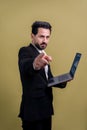 Businessman in black suit holding laptop pointing finger at camera. Fervent Royalty Free Stock Photo