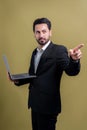 Businessman in black suit holding laptop pointing finger at camera. Fervent Royalty Free Stock Photo