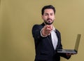 Businessman in black suit holding laptop pointing finger at camera. Fervent Royalty Free Stock Photo