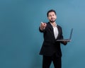Businessman in black suit holding laptop pointing finger at camera. Fervent Royalty Free Stock Photo