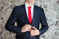 Businessman in black suit and a red tie. Smart casual outfit. Man getting ready for work. groom in a jacket, the groom fastens his Royalty Free Stock Photo