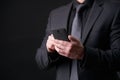 Businessman in black, trendy, modern and stylish suit using smartphone Royalty Free Stock Photo