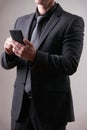 Businessman in black, trendy, modern and stylish suit using smartphone Royalty Free Stock Photo