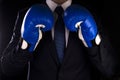 Businessman in blue boxing gloves on a dark background