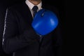 Businessman in blue boxing gloves on a dark background