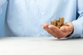 Businessman in a blue shirt holds in his hand lot of coins. Copy space for text. Royalty Free Stock Photo