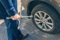 A businessman in a blue suit using cross wrench tighten the bolts wheel of punctured wheel. Hole in the tire.