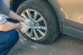 A businessman in a blue suit using cross wrench tighten the bolts wheel of punctured wheel. Hole in the tire.