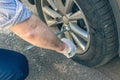 A businessman in a blue suit using cross wrench tighten the bolts wheel of punctured wheel. Hole in the tire. Concept.