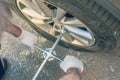 A businessman in a blue suit using cross wrench tighten the bolts wheel of punctured wheel. Hole in the tire. Concept.