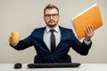 A businessman in a blue suit at a work table. Holds a folder with documents and a mug in his hands. Effective business work Royalty Free Stock Photo