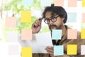 A businessman brainstorming ideas by writing them on sticky notes and sticking them to a glass wall Royalty Free Stock Photo