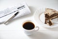 businessman breakfast. on the table a cup of coffee, a piece of cake, a newspaper and a pen.