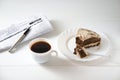 businessman breakfast. on the table a cup of coffee, a piece of cake, a newspaper and a pen.