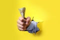 Businessman breaking through yellow paper with money in fist, closeup Royalty Free Stock Photo