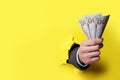 Businessman breaking through yellow paper with money in fist, closeup. Space for text Royalty Free Stock Photo