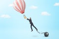 A businessman breaks away from a chain and iron ball to catch a small hot air balloon.