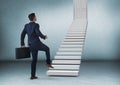 Businessman with briefcase walking up stairs to door