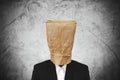 Businessman with brown paper bag on head, on dark concrete texture background Royalty Free Stock Photo