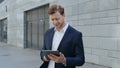 Businessman browsing internet on tablet at city. Employee using pad on street Royalty Free Stock Photo