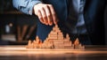 Businessman building pyramid of wooden blocks on table in office