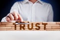 Businessman builds a structure of wooden blocks with the word trust. Building trust in business Royalty Free Stock Photo