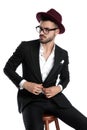 Businessman with burgundy hat sitting and fixing jacket Royalty Free Stock Photo