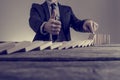 Businessman in business suit stopping dominoes row from crumbling Royalty Free Stock Photo