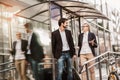 Businessman and businesswoman confidently walking through the urban city district while holding and dragging suit case Royalty Free Stock Photo