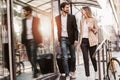 Businessman and businesswoman confidently walking through the urban city district while holding and dragging suit case Royalty Free Stock Photo