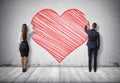 Businessman and businesswoman drawing big red heart on concrete wall Royalty Free Stock Photo