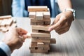 Businessman and Businesswoman hand placing or pulling wooden block Royalty Free Stock Photo