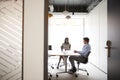 Businessman And Businesswoman Having Discussion Around Boardroom Table Viewed Through Meeting Room Door Royalty Free Stock Photo