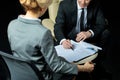 Businessman and businesswoman sitting on chairs and signing papers Royalty Free Stock Photo