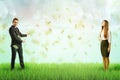 Businessman and businesswoman standing each at different side of green lawn with rain of dollar bills in the air. Royalty Free Stock Photo