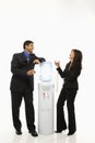 Businessman and businesswoman standing at water cooler. Royalty Free Stock Photo