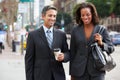 Businessman And Businesswoman In Street With Takeaway Coffee