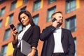 Businessman and businesswoman are talking on the phone while standing outdoors. Royalty Free Stock Photo