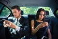 Businessman and businesswoman using smartphone in car Royalty Free Stock Photo