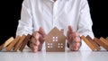 A businessman or a butler using his hand to protect the house from the falling of a wooden domino. Home protection insurance for s Royalty Free Stock Photo