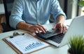 Businessman calculates with calculator, accounting docs at desk with laptop. Financial planning, data analysis, paperwork,