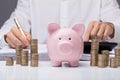 Businessman Calculating Bill With Piggybank And Stacked Coins Royalty Free Stock Photo